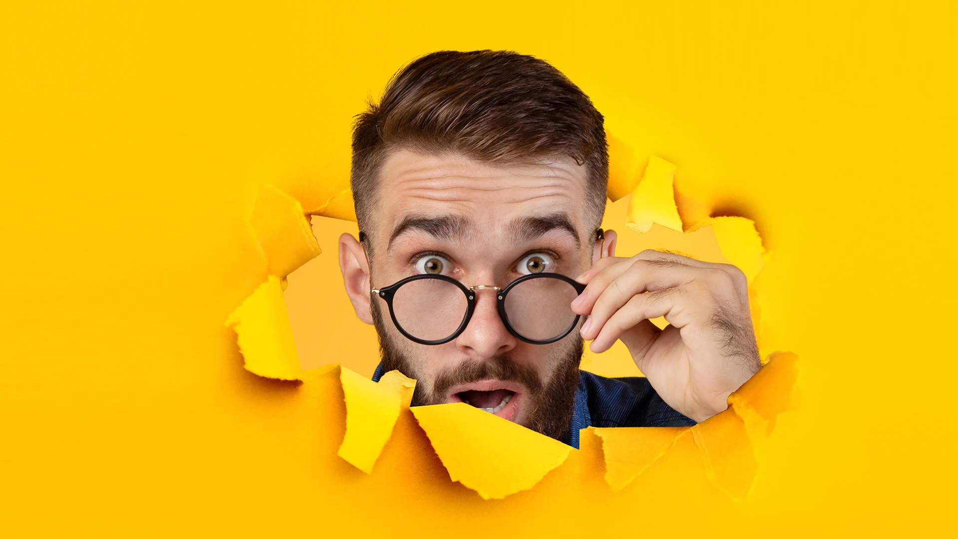 A man peeking through a yellow background to represent someone searching for your services and forming an opinion based on your B2B marketing